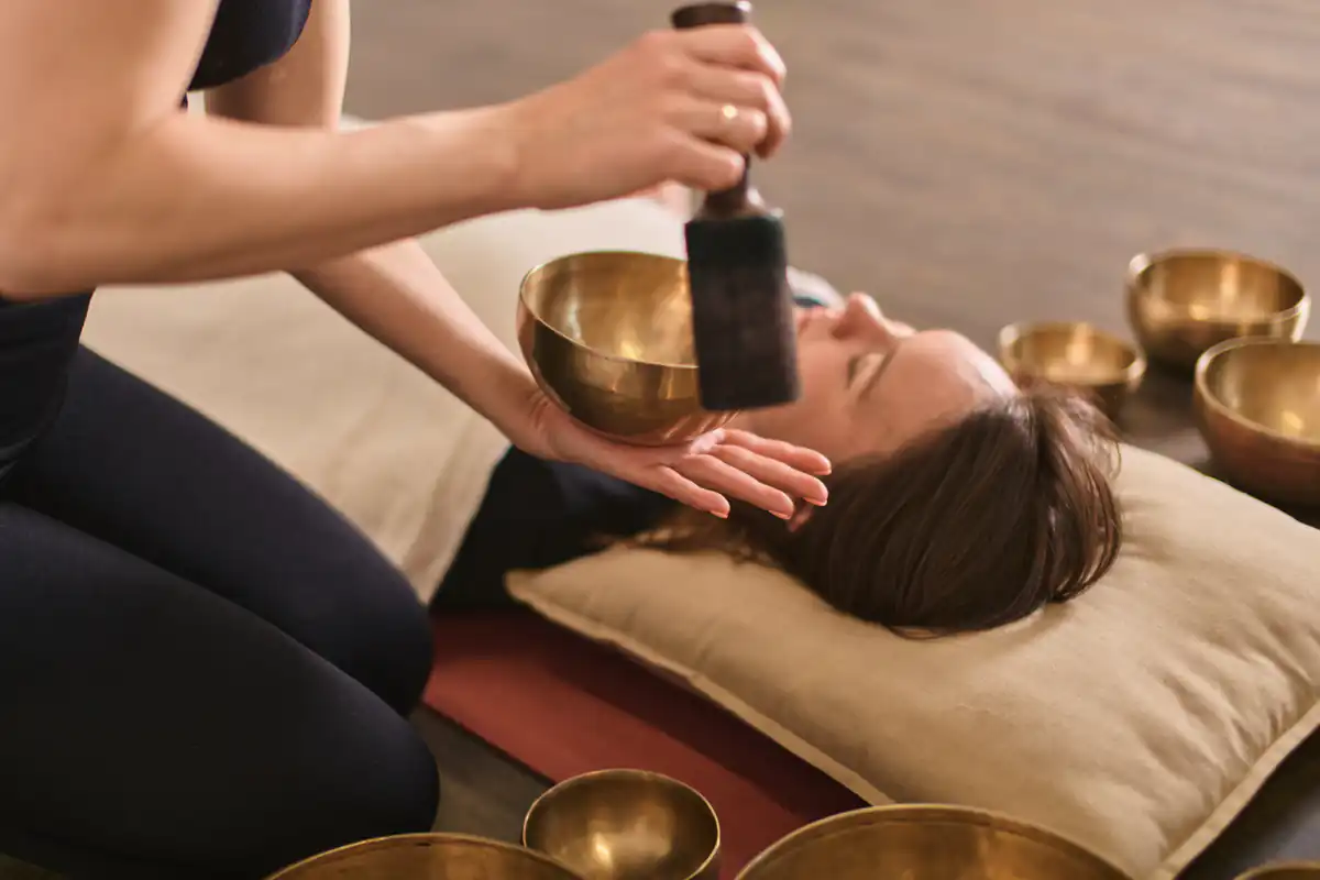 Sesja terapii dźwiękiem z misą terapeutyczną i osobą leżącą w relaksie.